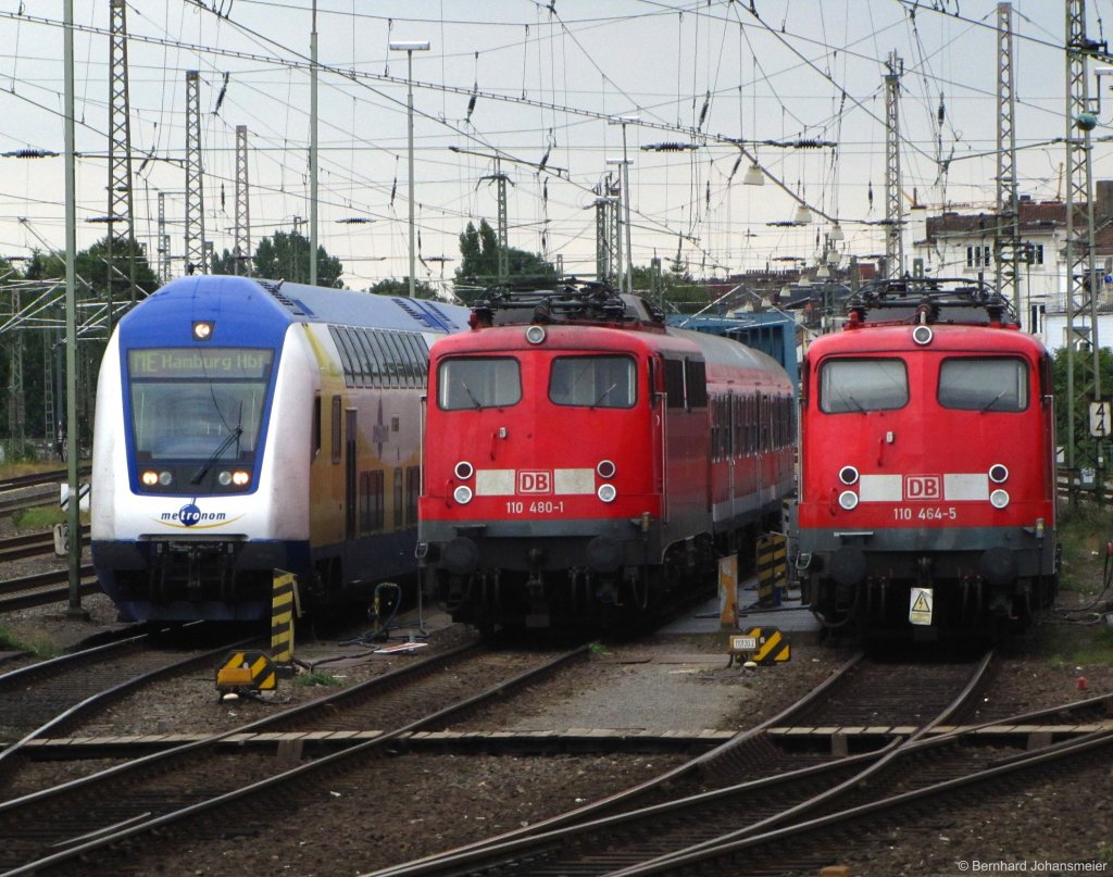 110 480-1 und 110 464-5 stehen mit Silberlingen neben einem Metronom in der Bremer Sdabstellung. Fotografiert aus fahrendem IC Richtung Hannover, August 2010