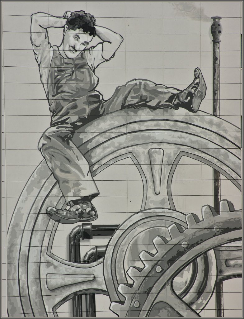 Etwas ratlos sitzt Charlie Chaplin vor der Technik...Eine Filmszene aus Moderns Times 1936. Anstelle neuer Farbe wurde bei zwei renovierungsbed�rftigen Hochh�usern diese Szene und noch einige andere nach Entw�rfen des K�nstler Franck Bouroullec an die W�nde gezaubert. Die H�usern kann man in Gilamont-Vevey von einem Aussichtspunkt aus gut bestaunen.  
(04.03.2012)