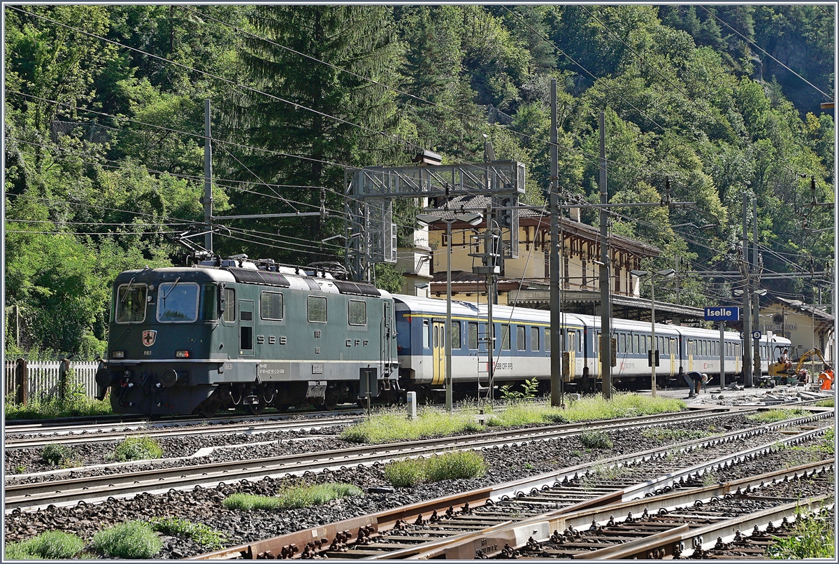 Baubedingte Sperrung der Simplonstrecke zwischen Iselle und Domodossola: Die SBB Re 4/4 II 11161 wartet mit ihrem IR 3220 in Iselle auf die Abfahrt nach Brig. Der Zug besteht aus folgenden Reisezugwagen: A 50 85 18 35 028-1, B 5085 20 35 265-1, B 50 85 20 316-2 und dem BDt 50 85 82 33 923-2. Das Bild entstand, indem ich meinen kleinen Fotoapparat (Coolpix 7900) durch den Gitterzaun schob und dann abdrückte. 

19. August 2020