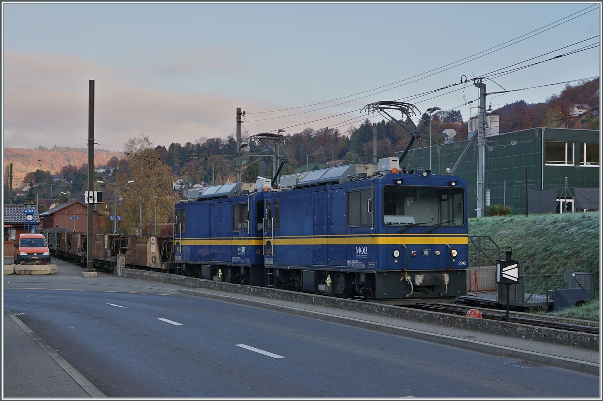 Die beiden MOB Gem 2/2 2502 und 2504 warten mit einem leeren Schotterwagenzug in Blonay auf die Abfahrt nach Chamby. 

9. November 2021