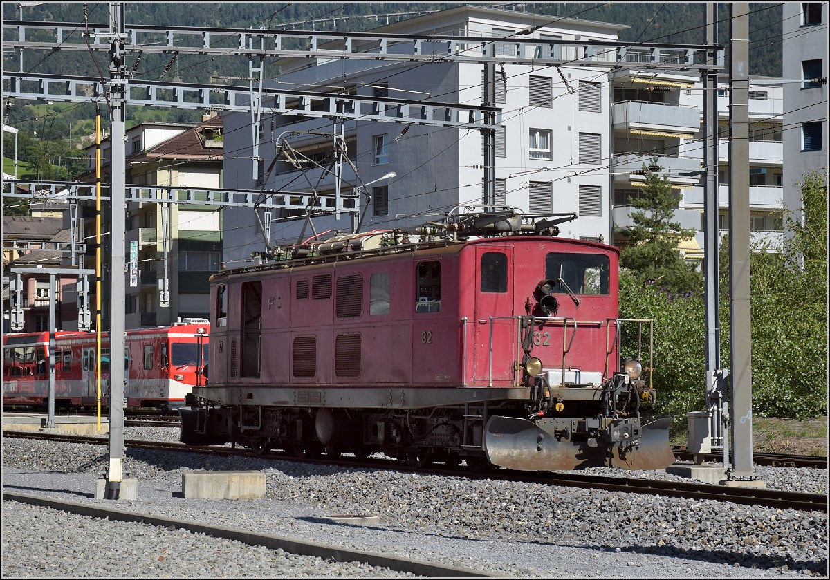 Die HGe 4/4 33 der MGB entschwand in Visp leider zu schnell, als dass sie ihn h�tte verfolgen k�nnen, so stand ich eingeschlossen auf der Nordseite des Bahn�bergangs. Noch ist das F der Furka-Oberalp-Bahn auf der Seite zu sehen, das O ist leider nur noch als Schatten zu sehen. Oktober 2017.