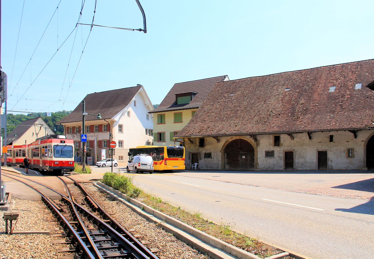 Die Pass-Strasse hinauf auf den Oberen Hauernstein wird von Bauten gesäumt, die der beschwerlichen Reise dienten, einerseits Herbergen und andererseits grosse Ställe für die Pferde; während Waldenburgerbahn Triebwagen 16 gerade aus Hölstein abfährt, schweift der Blick auf das uralte Gemäuer mit dem grossen Torbogen wohl eines Rasthauses aus dem Jahr 1566. 