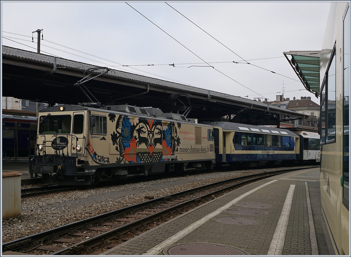 Eine MOB GDe 4/4 wartet in Montreux mit ihrem Panoramic Express auf die Abfahrt nach Zweisimmen. Das interessante dieses bildes ist der in Origainal-Farben zurückversetze ertse Wagen anlässlich des Jubiläums  40 Jahre-Panoram-Wagen .
14. Dez. 2016
