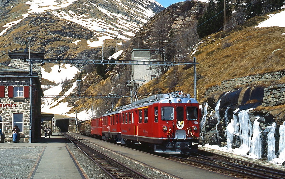 Mit zwei Holzwagen treffen der ABe 4/4 II 46 und ein weiterer ABe 4/4 II im April 1996 in der Station Alp Gr�m ein. Zwar ist der Schnee schon geschmolzen, doch das gefrorene Wasser zeigt, wie kalt die N�chte noch waren.