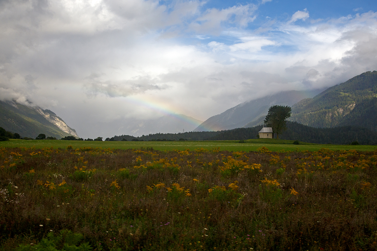 Regenbogen über der kleinen Baselgia Sogn Mang bei Bonaduz (Churer Rheintal) am 12.09.2017 aus einem RhB-Zug heraus fotografiert.

Die kleine Feldkapelle Sogn Mang auf der Bonaduzer Terrasse wurde 1773 erbaut und 1993 restauriert. Sie ist dem heiligen Magnus (romanisch: Sogn Mang) geweiht und gehört zur kath. Pfarrei Mariä Himmelfahrt Bonaduz. Die besondere Lage auf dem offenen Feld mit den beiden mächtigen Pappeln lädt zum Verweilen ein.