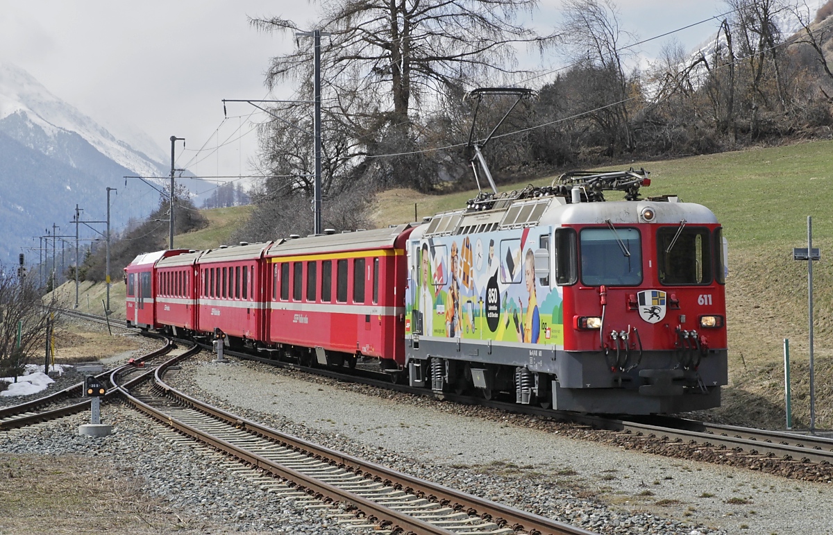 Von den 23 in zwei Serien beschafften Ge 4/4 II stehen bis auf die nach einem Unfall abgebrochene 628 alle Lokomotiven noch im Dienst. Die 611  Landquart  wurde als erste Ge 4/4 II am 30.05.1973 in Betrieb genommen. Seit 2008 wirbt sie für die Login Berufsausbildung AG. Hier kommt sie am 02.04.2022 in Scoul-Tarasp an.