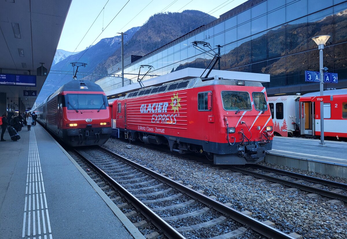 Während die MGB HG 4/4 II N° 4 mit ihrem Regio von Zermatt in Visp für die Rückfahrt nach Zermatt wendet, erreicht eine SBB Re 460 mit ihrem IR 61 von Brig nach Basel den Bahnhof von Visp. 

18. Februar 2025