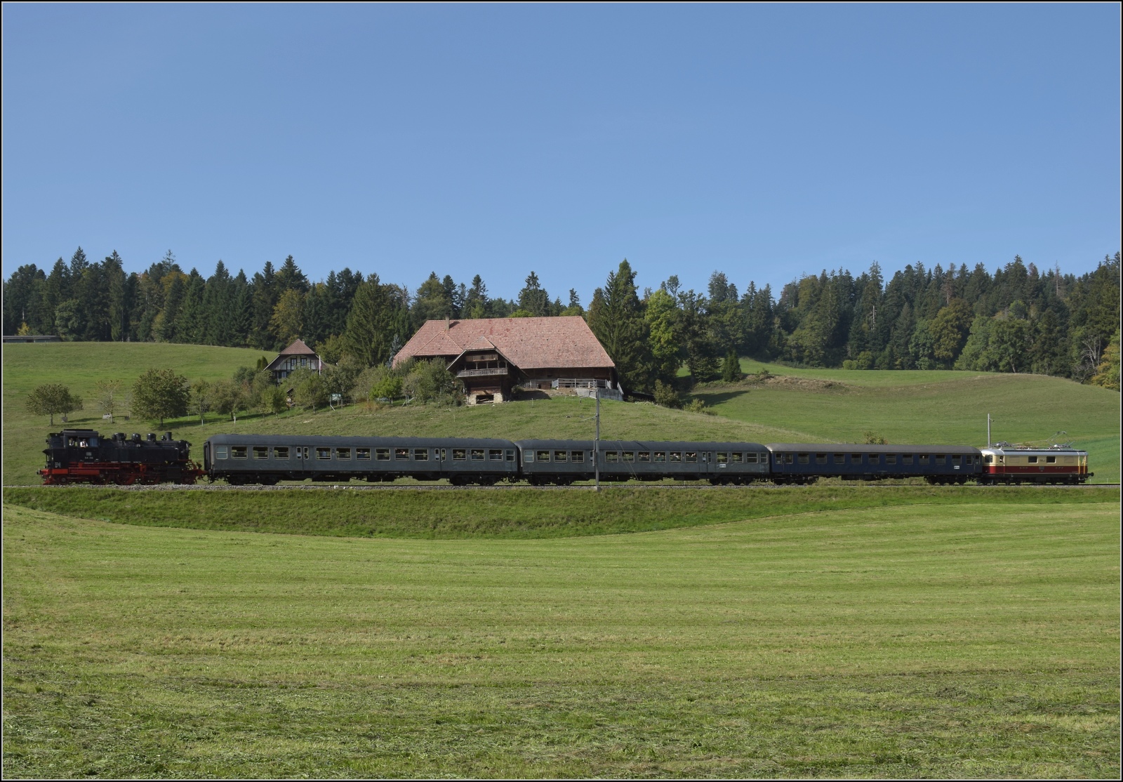 Dampftage Huttwil mit frisch genesenem Bubikopf. 

Bei Wydithub rollt 64 518 nach Sumiswald-Grünen hinunter, dahinter die 'neuen' Eurovapor-Silberlinge, ein Am-Schnellzugwagen und Re 4/4 I 10034 zur Unterstützung. Oktober 2023.