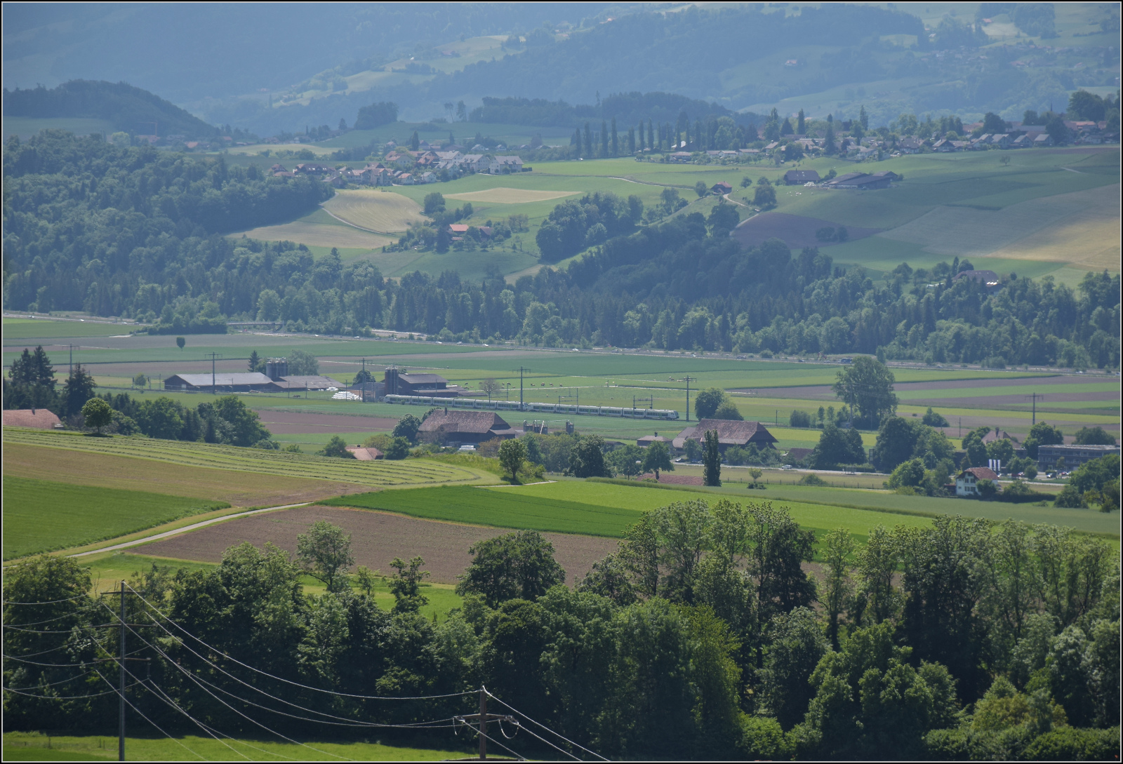 Der Blick darf auch mal in die Ferne schweifen, im Aaretal fährt bei Münsingen eine Doppeltraktion Mika RABe 528 in Regionalzugversion vorbei. Mai 2025.
