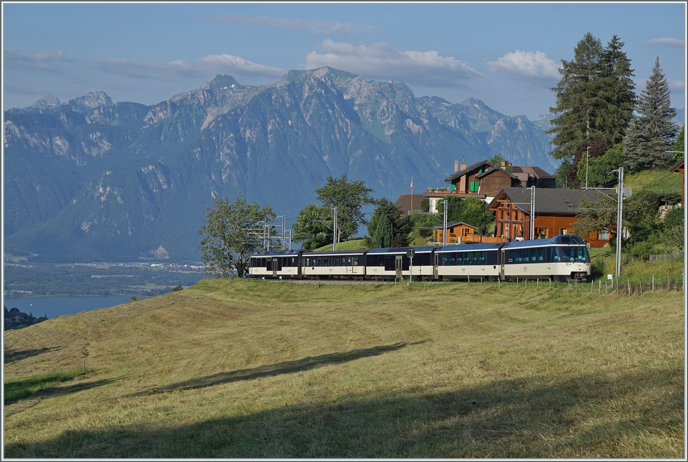 Der MOB ABe 4/4 9302 (Alpina) an der Spitze des Zugs ist mit dem Regionalzug R 30 2207 von Zweisimmen nach Montreux bei Les Avants unterwegs. 
Links sieht sogar noch ein Stück des Genfer Sees. 

28. Juni 2024
