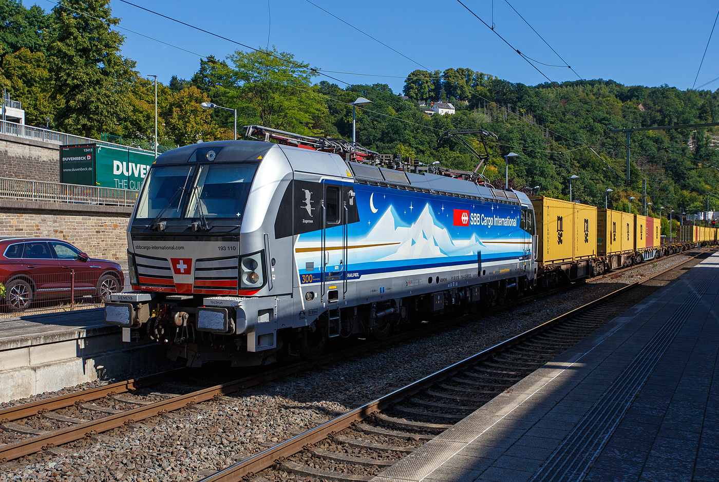 Die an die SBB Cargo International AG vermietete Siemens Vectron MS - 193 110  Zugersee  (91 80 6193 110-4 D-Rpool) der Railpool GmbH (München) fährt am 18 August 2025 mit einem Containerzug durch den Bahnhof Kirchen/Sieg in Richtung Siegen. 

Die SIEMENS Vectron MS (X4E) wurde 2023 von Siemens Mobility in München-Allach unter der Fabriknummer 23293 gebaut. Die mit 6.400 kW konzipierte Mehrsystemlok ist in der Variante A22 ausgeführt und hat so die und hat so die Zulassungen und entspr. Länderpakete für Deutschland, Österreich, Schweiz, Italien und die Niederlande (D / A / CH / I / NL), wobei z.Z. CH und I noch durchgestrichen sind. Sie ist die 300th Lokomotive der Railpool. 