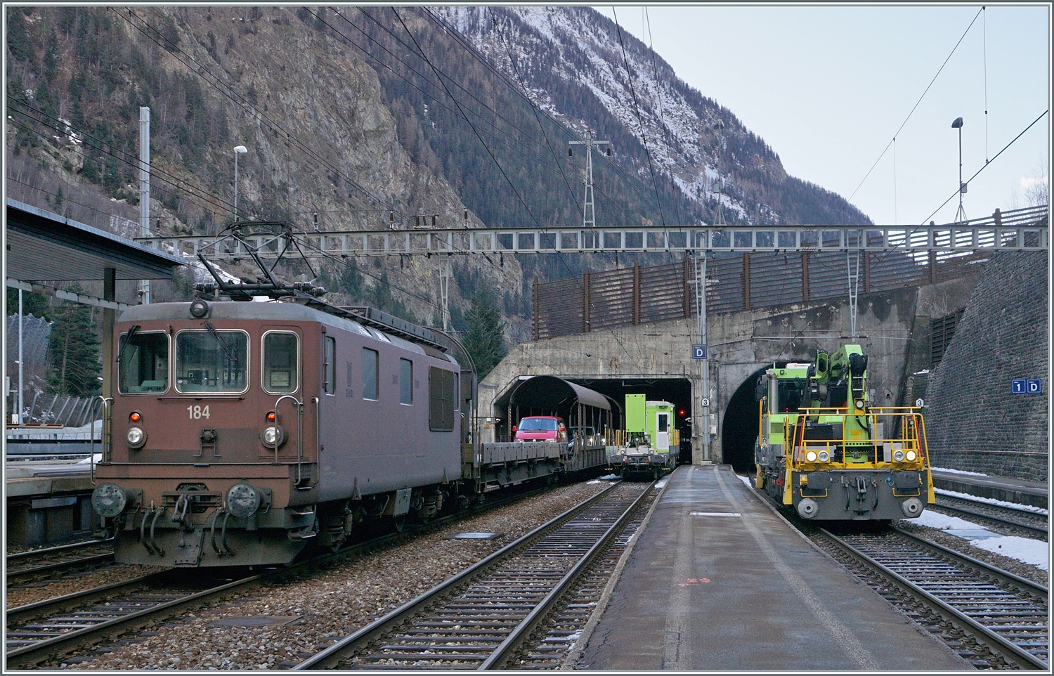 Die BLS Re 4/4 184 wartet in Goppenstein mit ihrem AT1 Autotunnelzug auf die Abfahrt, während auf Gleis zwei der BLS Tm 232 204-5 (UIC Tm 98 85 5232 204-5 CH-BLSN) rangiert. 

3. Jan. 2024