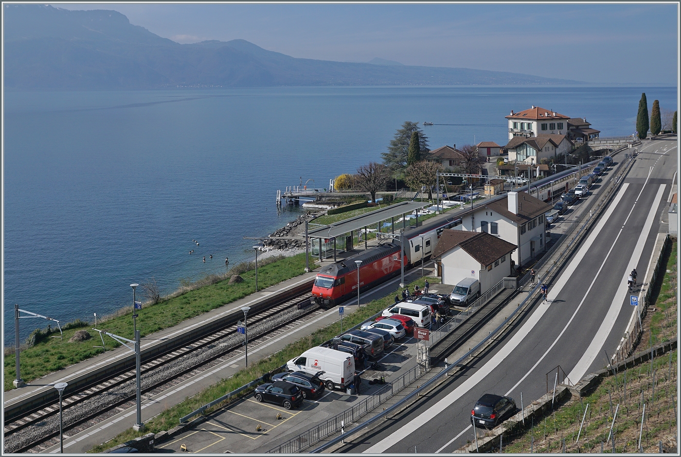 Ein Blick auf den Bahnhof von Rivaz, welcher zwar nie grosse Bedeutung hatte, aber in den letzten Jahren doch im Sinne der betrieblichen Optimierung doch etwas  Federn  lassen musste: Seeseitig war auf dem jetzt grünen Streifen ein Abstellgeleis angeordent, die beiden Hautgeleise war durch eine Weichenverbindung verbunden, die jetzt sinnvollerweise ausserhalb der Bahnsteige angeordnet wurde und Bergseitg war ebenfalls ein Abstellgeleis bzw. Güterschuppen angeordnet. Zudem war ausserhalb des Bahnhofs in Richtung Lausanne ein Anschlussgleis einer Mühle vorhanden, welches bis in die 1980 für etwas Güterverkehr sorgte. 
Im Bild eine SBB Re 460 mit einem IR 90 auf der Fahrt von Genève Aéroport nach Brig. 

30. März 2025