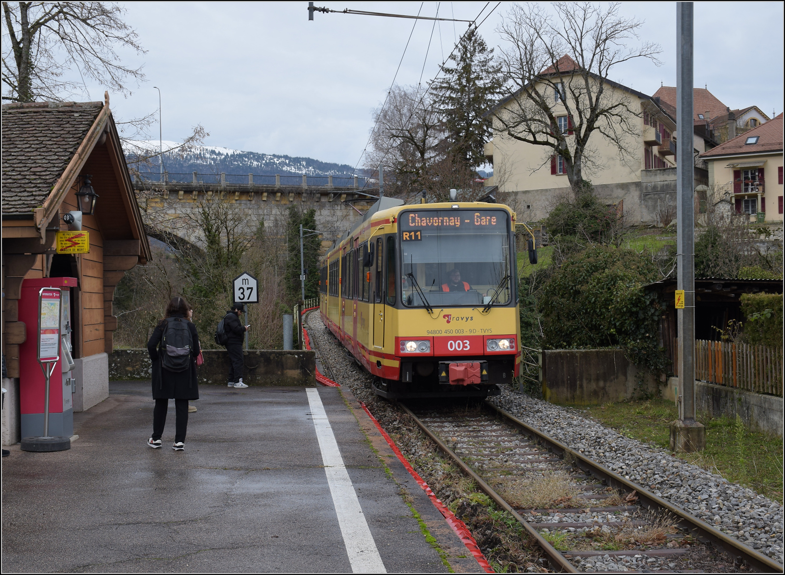 Ende einer �ra - der Gleichstrom und die  Lokalbahn  gehen. 

Halt der Karlsruher Zweisystem-Strassenbahn  Be 4/8 003  alias 94 800 450 003-9 D-TVYS in St. Eloi, kaum dass die Fahrt im Bahnhof begonnen hat. Der Bahnsteig reicht gerade so eben f�r die Strassenbahn aus. Wohin der geplante 110 m Bahnsteig erweitert werden soll, entzieht sich meiner Kenntnis, aber ich stehe beim Fotografieren bereits auf der Stra�e, das Fahrzeug ist selbst aber noch auf der Orbe-Br�cke. Orbe, Dezember 2025.