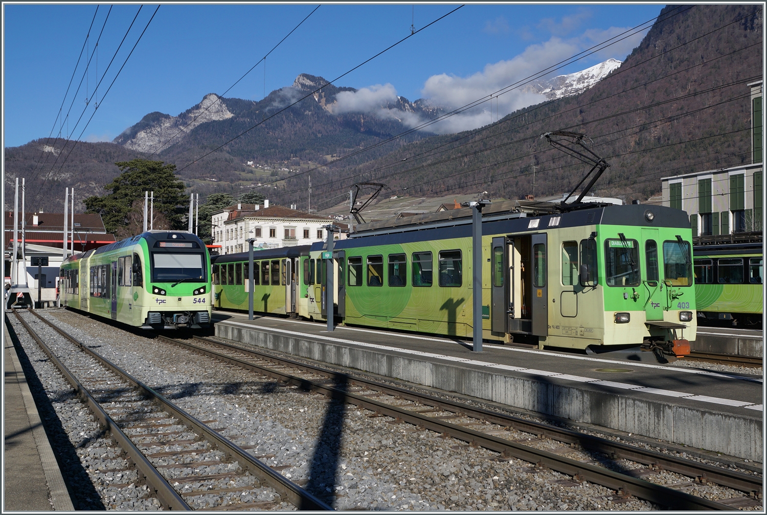 Links wartet der TPC AOMC/ASD Bhe 2/6 544 als R 72 in Richtung Monthey auf die Abfahrt und daneben der ASD Regionalzug (R71) mit dem führenden BDe 4/4 403. 

17. Feb. 2024