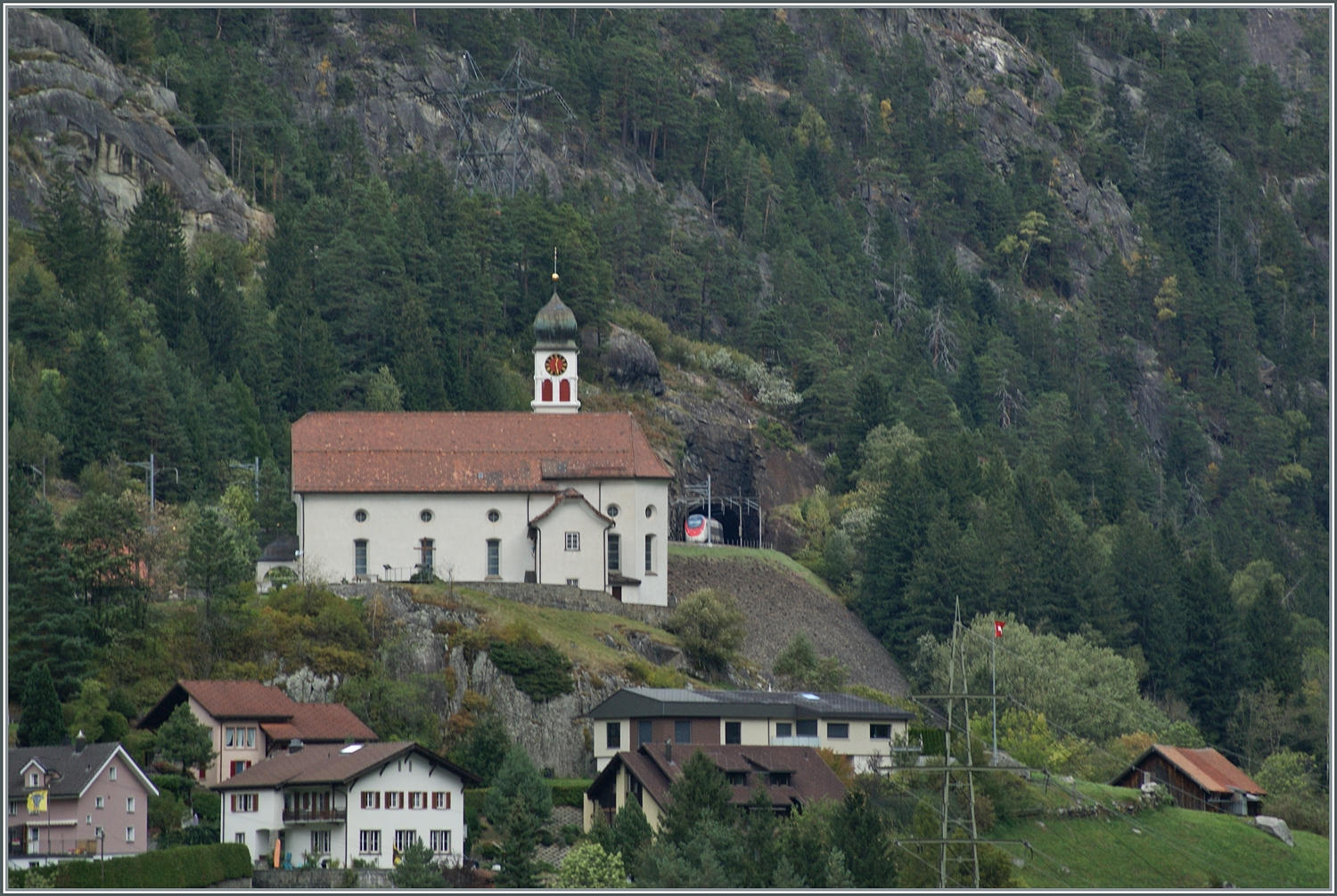  s Chiläli vo Wasse  /  die Kirche von Wassen , ziemlich weltberühmt, auch wenn durch den GBT die meisten Reisenden in den Süden nicht mehr in den Genuss kommen die Kirche von Wassen drei mal zu sehen. Versteckt im Bild ist der SBB  Giruno  RABe 501 016  Glarus  als IC 2 von Zürich nach Lugano bei Wassen nun auf der mittleren Ebene bei Wassen unterwegs.

19. Okt. 2023