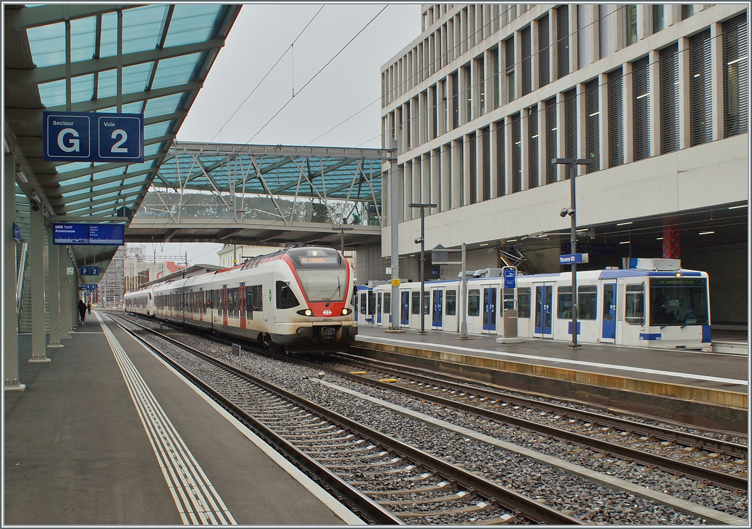 Zwei SBB Flirt verlassen Renens VD nach Vallorbe und Le Brassus (Flügelzug). Im Hintergrund ist ein TL TSOL Be 4/6 als m1 zu sehen. 

14. Dez. 2023