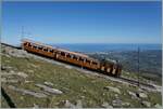 Kurz nach der Gipfelstation La Rhune (905 müM) ist die 1914 von der SLM/BBC gebaute Chemin der fer de la Rhune He 2/2 mit Vmax 9 km/h mit ihrem ersten Zug des Tages auf der Fahrt ins  Tal , wobei mit  Talstation  der Passübergang Col de Saint-Ignace auf 198 müM gemeint ist. Im Hintergrund gleitet Blick über den mächtigen Atlantik sowie die beiden Orte Ciboure und Saint-Jean-de-Luz.

12. April 2024